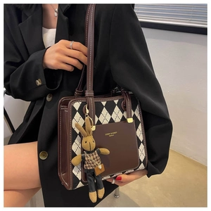 Close-up of vintage brown leather and argyle fabric handbag with a plush bunny charm