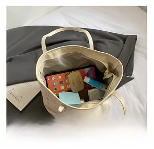 Spacious interior of beige leather tote bag holding a tablet and cosmetics