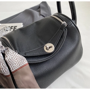 Detailed close-up of black litchi grain leather bag with silver buckle and silk scarf
