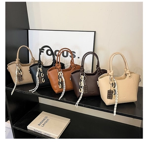 Detail view of five textured bucket bags in khaki, black, caramel, and cream colors