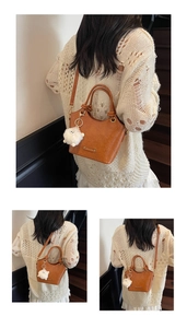 Detail of caramel leather bucket bag with litchi texture and gold metal logo charm