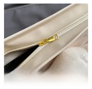 Close-up of golden metal zipper hardware on creamy white synthetic leather tote bag