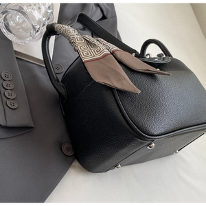 Detail of black leather handbag with silk scarf handle and silver bottom studs