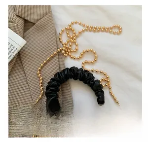 Dettaglio borsa nera texture coccodrillo con catena dorata e manico a pieghe