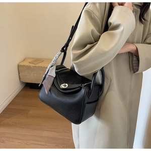 Detail of black leather pillow bag with silk scarf and silver metal turn-lock closure