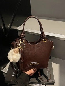 Brown vintage glossy leather bucket bag with white plush charm and round handle