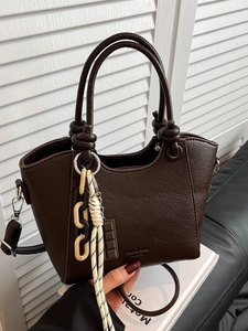 Brown leather bucket bag with top handles and chunky chain strap shown held by hand