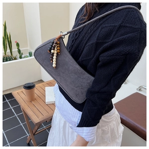 Détail du sac bandoulière gris foncé en similicuir avec pompon décoratif en perles de bois