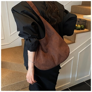 Rear view of model wearing a large brown suede hobo bag with a minimalist wide shoulder strap