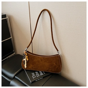 Détail du sac baguette marron mat vintage avec pompon en perles et bandoulière