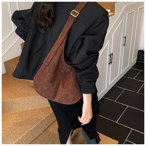 Detail of a brown hobo bag showing adjustable strap and gold-tone square hardware