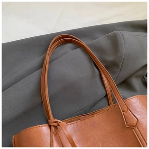 Close-up of fine stitching and durable strap attachment on a vintage brown tote bag