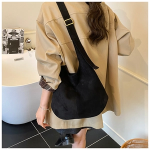 Detail of black suede hobo bag with adjustable wide shoulder strap and gold buckle