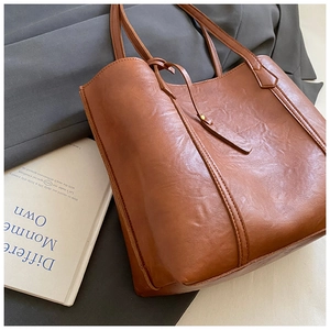 Detailed shot of brown vintage faux leather tote bag with metal buckle and slim handles