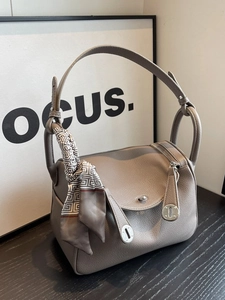 Elegant elephant gray leather pillow handbag with decorative scarf on a wooden table