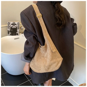 Detailed side view of khaki suede tote bag with adjustable wide shoulder strap and gold buckle