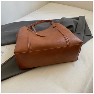Détail du sac cabas marron vintage montrant le grain du cuir et les poignées renforcées