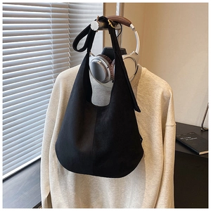 Detail of black suede hobo bag with wide shoulder strap and adjustable metal buckle