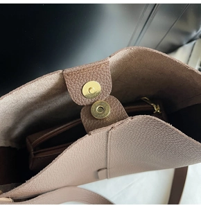Detail view of large brown pebble leather tote bag with gold magnetic clasp closure