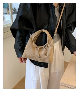 Detailansicht der beigefarbenen Wildledertasche mit dekorativer Schleife und Schultergurt
