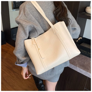 Gros plan d'un sac cabas crème en cuir avec texture plissée fine et détail de la bandoulière