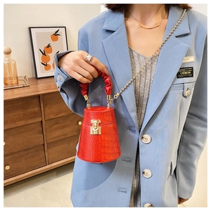 Dettaglio borsa a secchiello rossa con trama a coccodrillo e manico arricciato