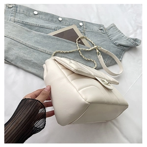 Detail view of cream white quilted crossbody bag with gold chain strap and V-stitch pattern