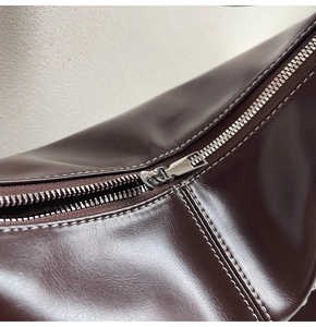 Détail du sac cabas en cuir marron foncé avec coutures blanches et zip argenté