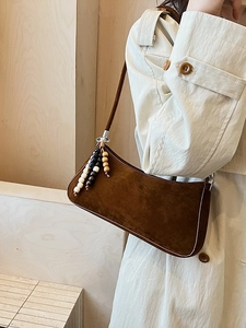 Sac à bandoulière marron mat vintage avec breloque en perles porté par un mannequin