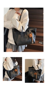 Close-up of black leather tote bag with brown plush bear charm and tassel detail