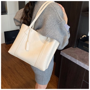 Grand sac cabas crème avec doubles poignées et détails de coutures sur un mannequin