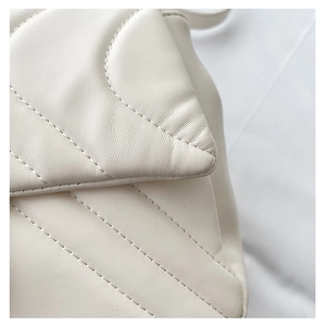 Detail shot of white quilted leather texture and premium V-shaped stitching on the bag