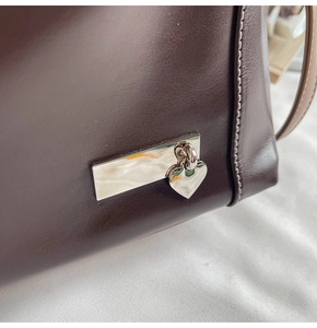 Détail du cuir marron de qualité avec pendentif en forme de cœur sur le sac fourre-tout