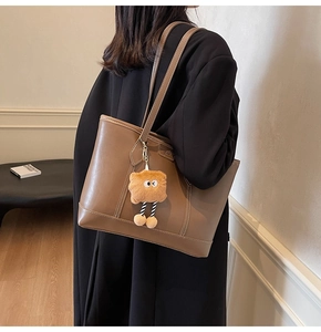 Détail d'un grand sac cabas marron avec surpiqûres et pendentif en peluche