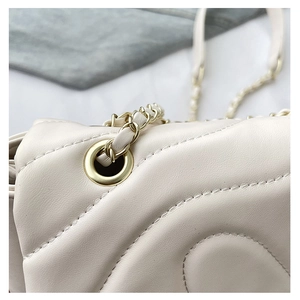Detailed view of cream quilted shoulder bag with gold hardware and chain strap details