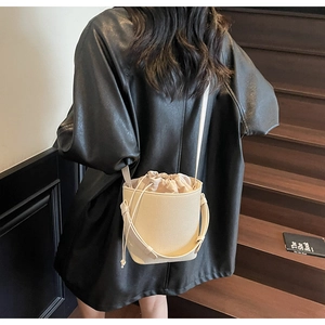 Detalle del bolso tipo cubo crema con bolsa interior ajustable y correa de hombro
