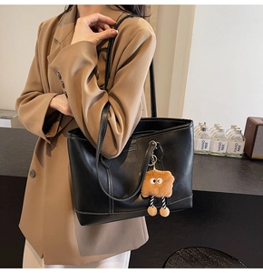 Détail du sac cabas noir avec coutures contrastées blanches et charm toast en peluche