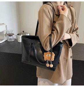 Détail d'un cabas noir avec surpiqûres blanches et pendentif en peluche mignon