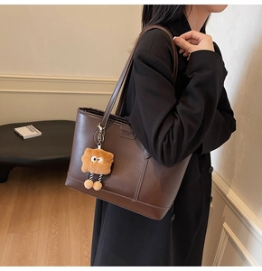 Détail du grand sac cabas en cuir marron foncé avec surpiqûres blanches et charme peluche