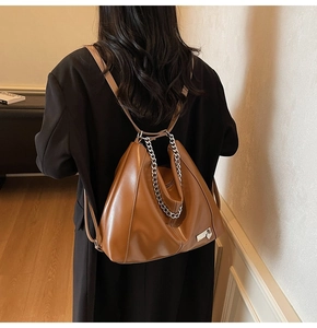 Vue arrière du mannequin portant un sac fourre-tout en cuir marron avec chaîne argentée