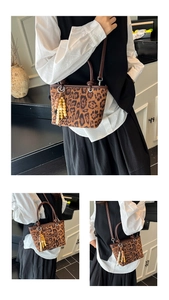Detail view of leopard print bucket bag with brown leather handles and bead charm