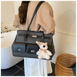 Detail of a large two-tone leather tote bag with silver turn-lock pockets and a cute bear charm