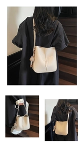Detail of cream pebbled leather bucket bag with a brown fur ball charm on wooden stairs