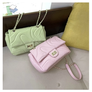 Detail of quilted flap chain bags in pink and green colors with gold turn-lock hardware