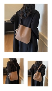 Detailed view of brown lychee grain leather bucket bag with plush bear charm and long strap