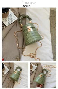 Dettaglio della trama a coccodrillo verde e della catena dorata sulla borsa a secchiello
