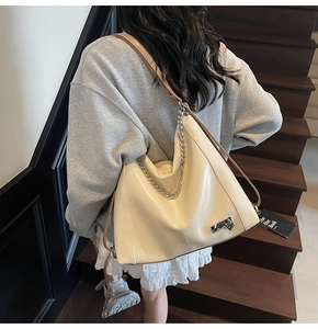 Détail d'un sac cabas crème avec chaîne argentée et bandoulière marron en escalier