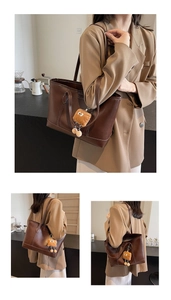 Détail d'un sac cabas marron avec un pendentif en peluche toast et un design spacieux