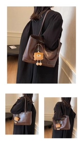 Détail d'un grand sac cabas en cuir marron avec surpiqûres blanches et charme monstre en peluche