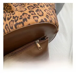 Detailed close-up of leopard print fabric and brown leather base with gold metal zipper